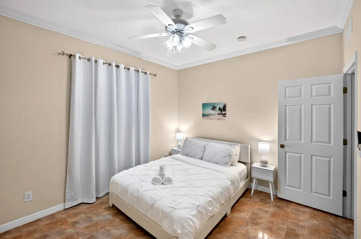 Bedroom with a bed, white curtains and a ceiling fan