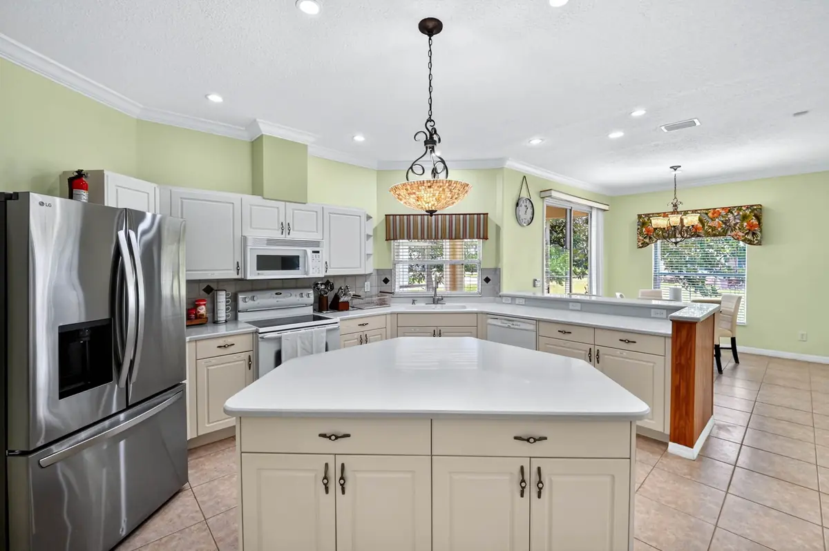 Kitchen with a large island, stainless refrigerator and white cabinets